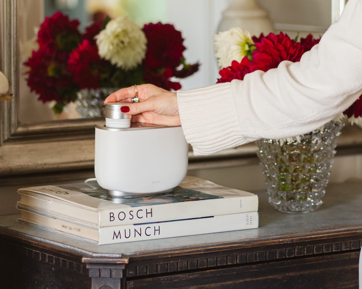 Person inserting a diffuser fragrance or scent capsule into an Aera smart home diffuser to help scentscape a room. This is the main header image of the Scentscape blog post